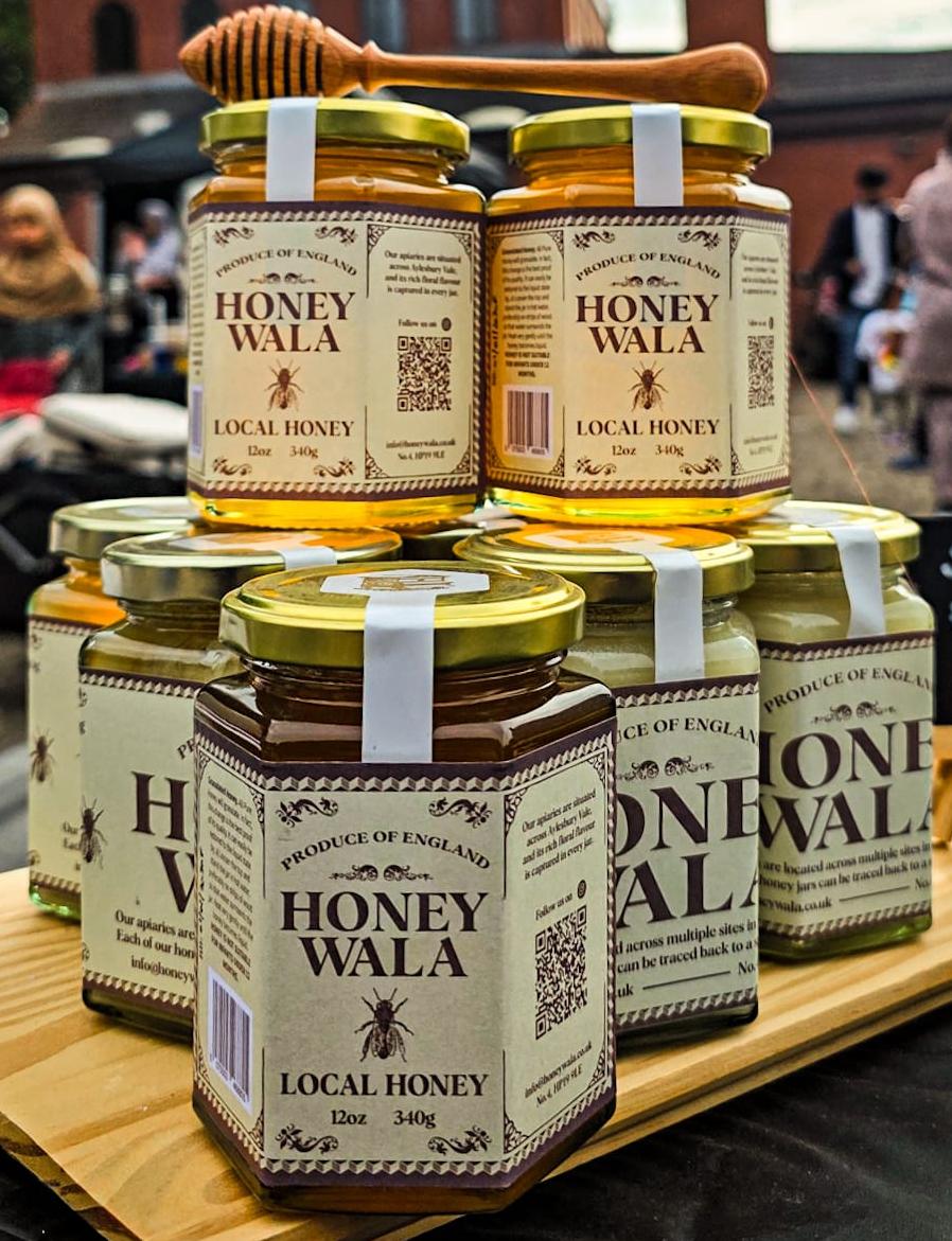 Stack of Honey Wala jars in a meadow at golden hour